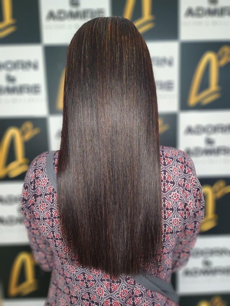 Dark brown hair with warm caramel highlights, straight finish