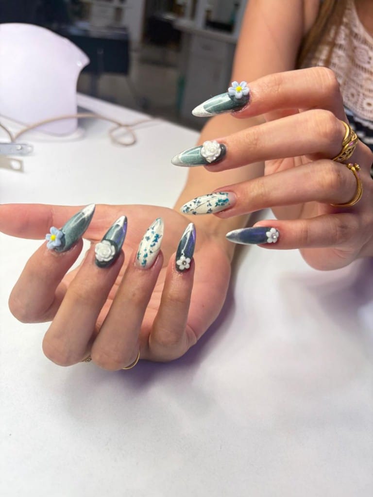Teal cat-eye nails with 3D floral charms and botanical accent nails
