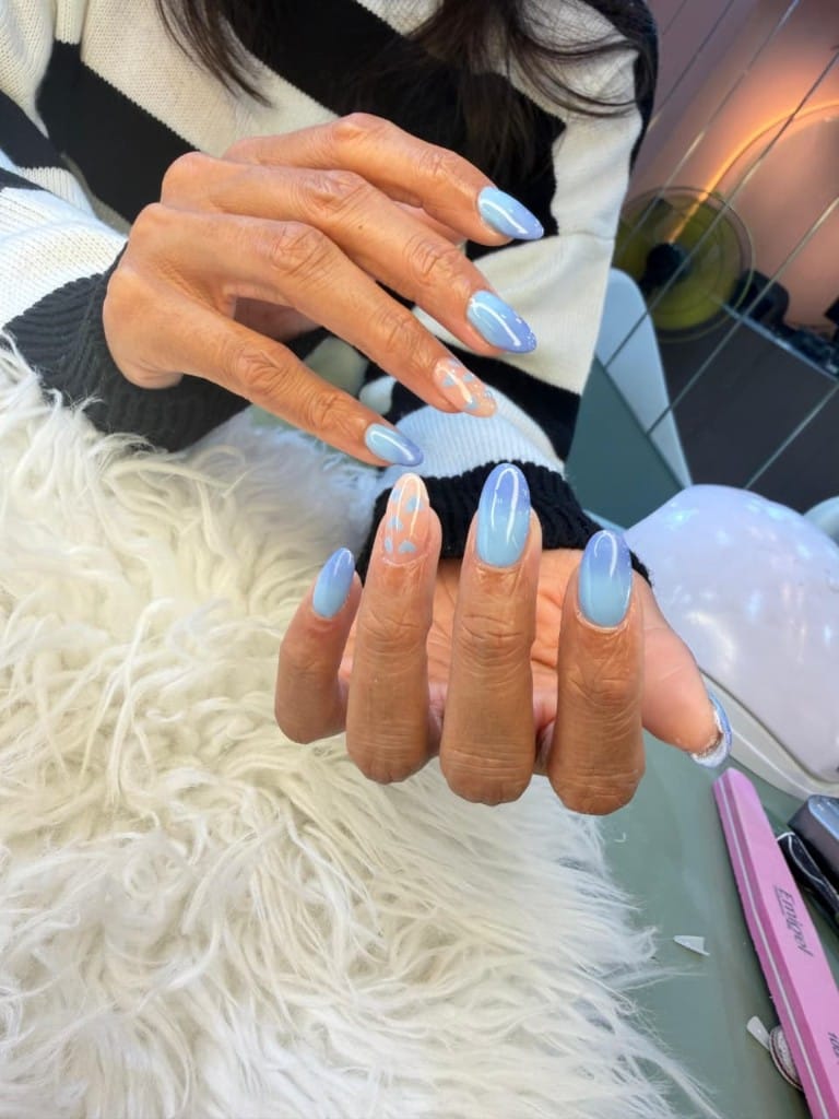 Sky blue ombre almond nails with hand-painted hearts on a nude accent